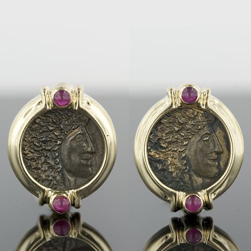 Brightly Polished 14 Karat Yellow Gold Neo-Classic Style Bezel Earrings, Highlighted with Ruby Cabochons are the Frames for the Pair of Replica Ancient Coins Encased. The Coins, Having an Oxidized Finish, Depict the Profile of a Greco-Roman Emperor.