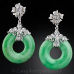 A Pair of Apple Green Jadeite Pi earrings, each Surmounted by Elegantly Fashioned Diamond-Set Tops, c.1930s.